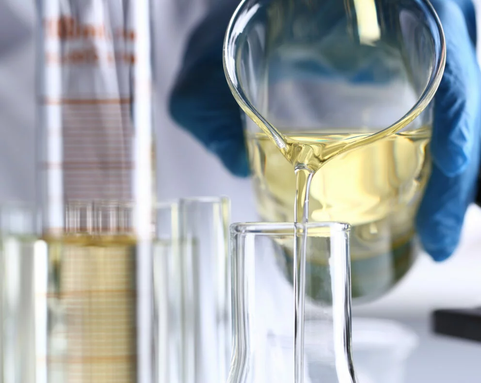 technicien versant un échantillon de carburant dans un tube pour analyse en laboratoire