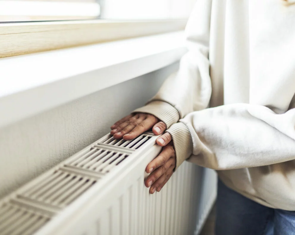 personne posant ses mains sur un radiateur illustrant le chauffage au fioul domestique