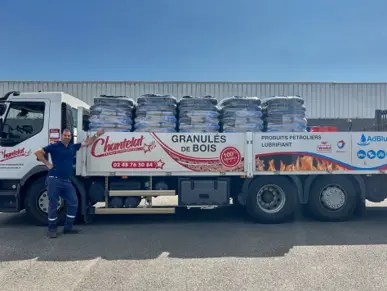Camion de livraison chargé de sacs de granulés de bois avec un opérateur professionnel.