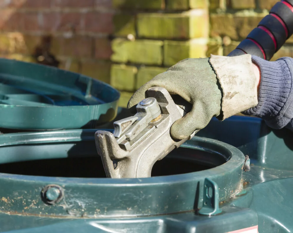 main équipée d'un gant introduisant pistolet de remplissage dans l’ouverture d’une cuve fioul double paroi